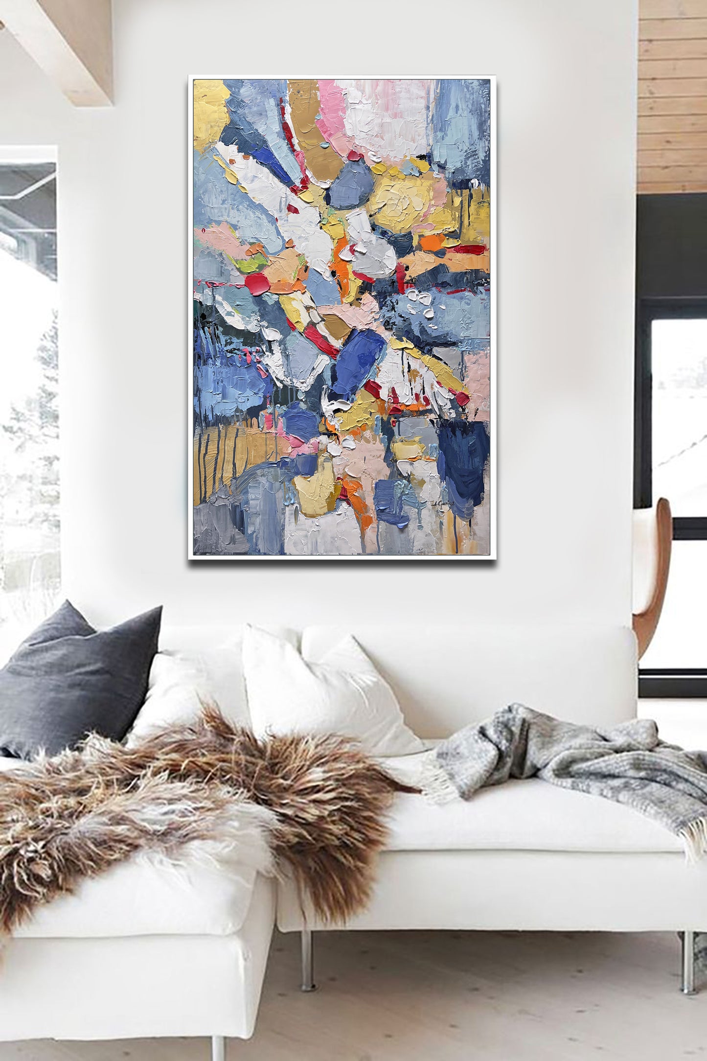 a living room with a white couch and a painting on the wall