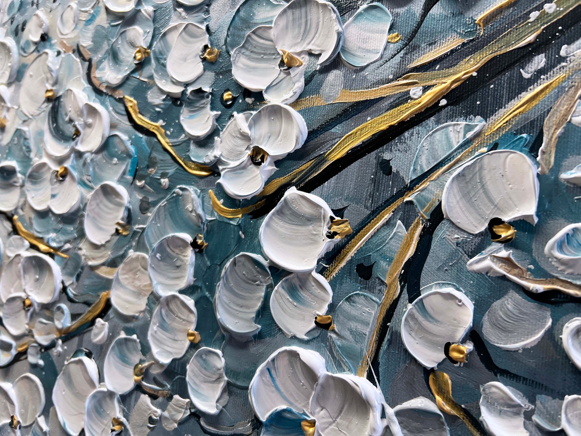 a close up of a painting with white and gold paint